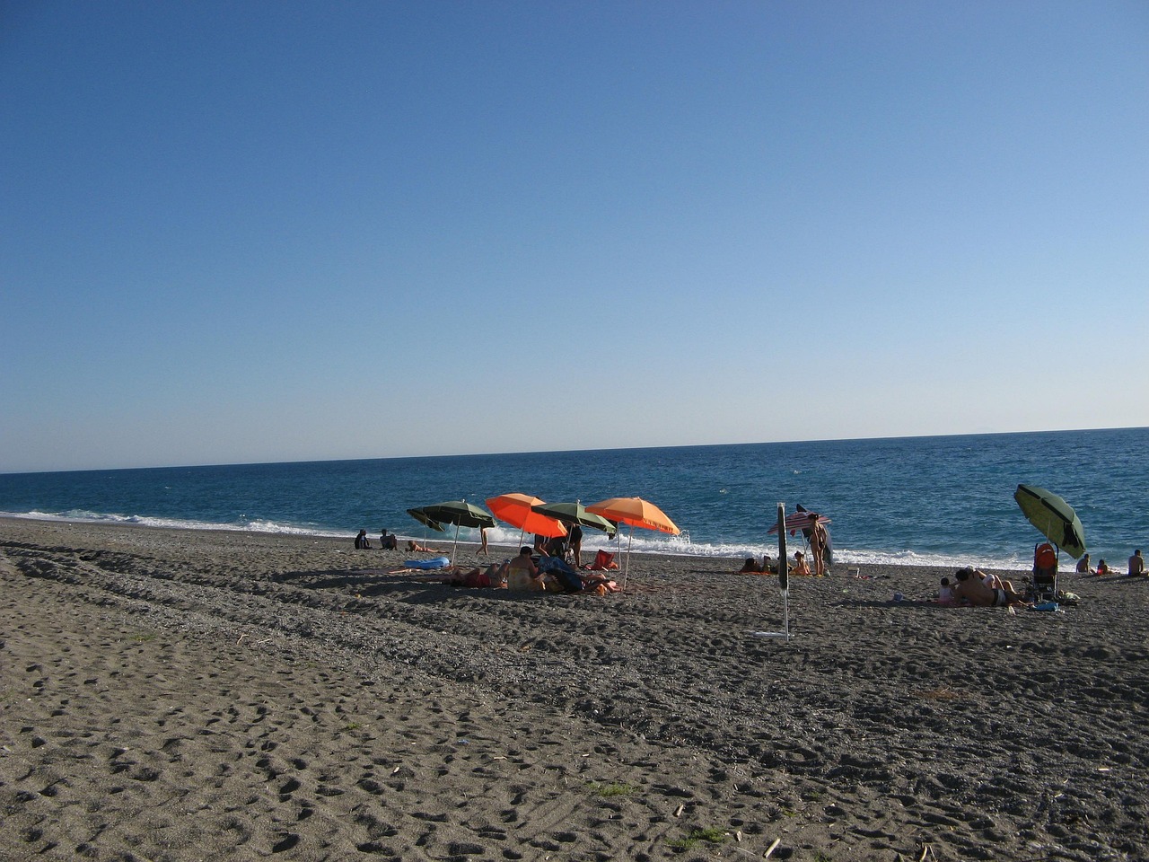 Spiaggia nera vulcanica con onde che si infrangono, simile a quelle delle Hawaii.